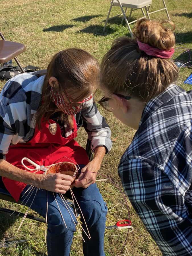 Mary Smith shows UA student Riva Cullinan how to weave a basket.