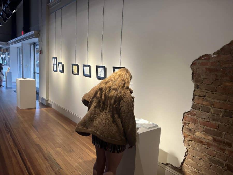 A person leans over a display at the Book Arts exhibit.