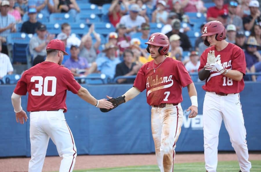 Jake Leger (30) and Drew Williamson (18) congratulate Alabama center fielder Caden Rose (7) on his way back to the dugout in the Crimson Tides 12-8 loss to the No. 2 Texas A&M Aggies on May 27 at Hoover Metropolitan Stadium in Hoover, Alabama.